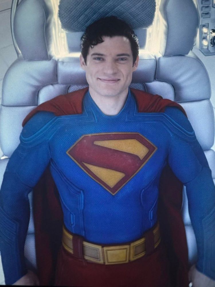 Overhead shot of Superman reclining in a chair, looking back up, smiling.