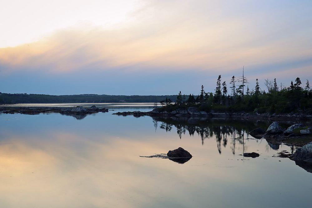 Sunset on the Salt Marsh Trail. Orange and blue light, mirrorlike water, pine covered island with sharp reflection.