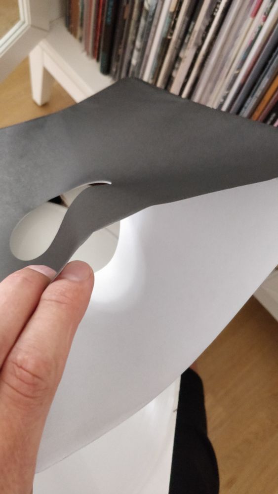 A plain paper record sleeve being held open to fully demonstrate its record-scratching properties.