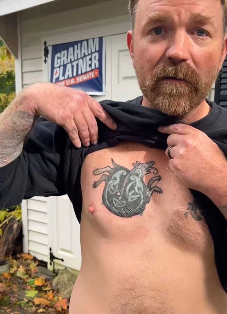 Graham Platner showing off the tattoo of Fenrir swallowing the world that he got to cover up his Nazi totenkopf