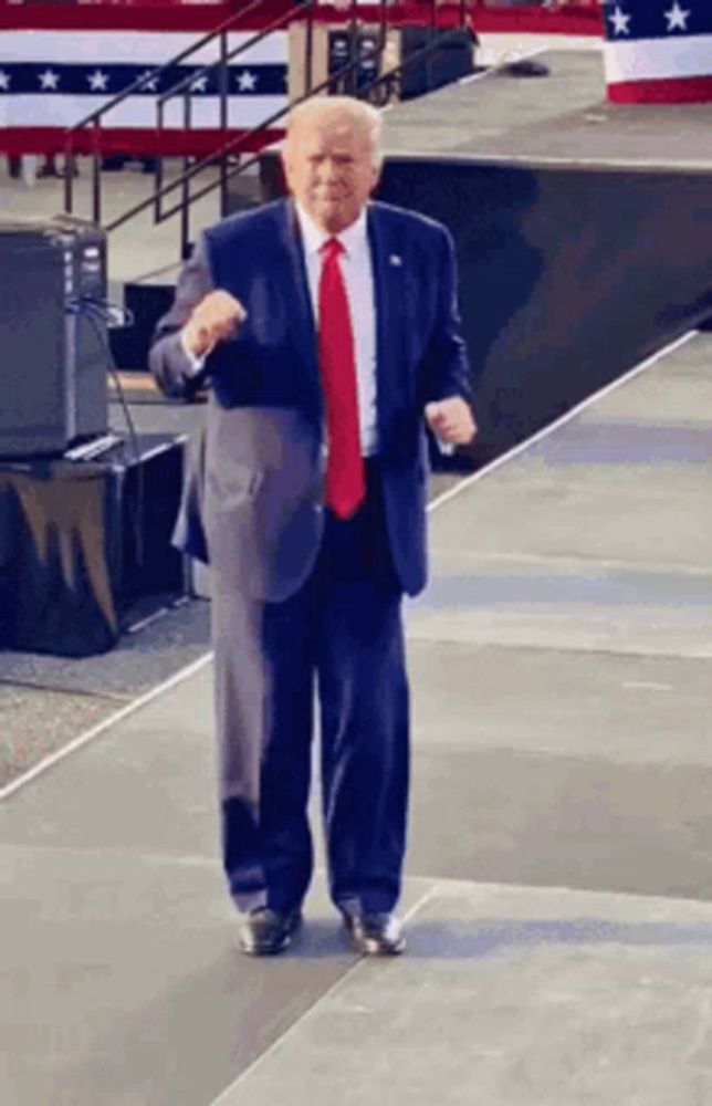 a man in a suit and red tie is standing on a stage