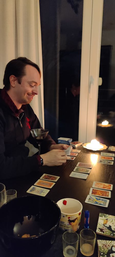 A person sitting in front of a table with a set of tarot cards arranged in a reading pattern.