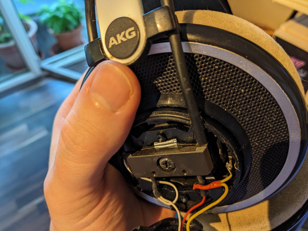 Partially taken apart filthy headphones with an overly thocky (albeit perfectly functional) solder joint at the end of the yellow wire.