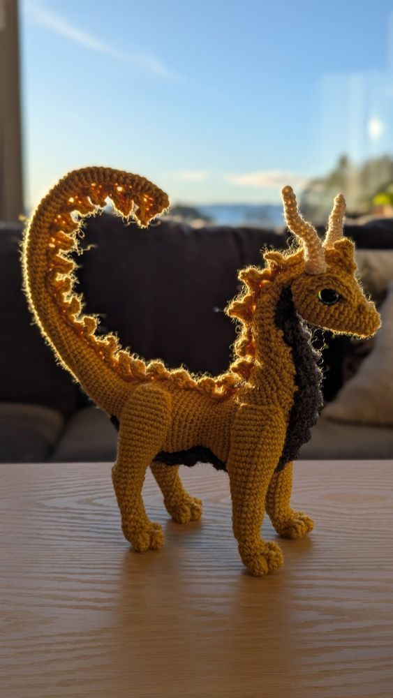 A yellow crochet dragon standing on four legs. 