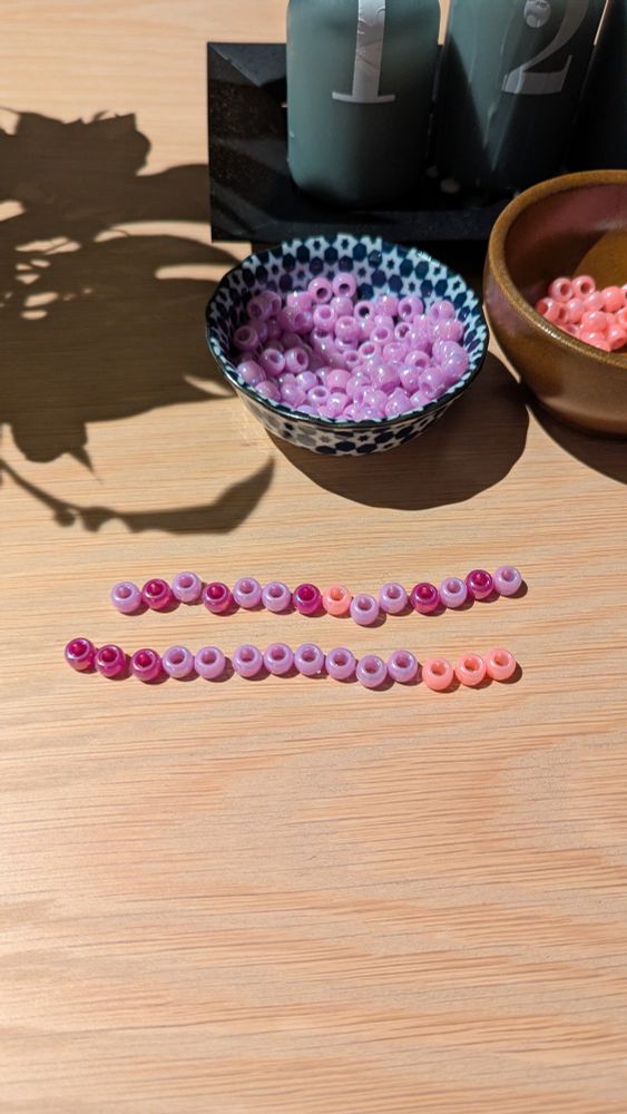 Two rows of beads on pink, purple and dark purple.