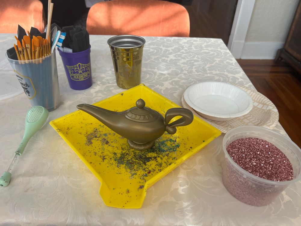 Plastic genie lamp and supplies to decorate it: glitter, glue, brushes etc. and a beverage for me to enjoy. 