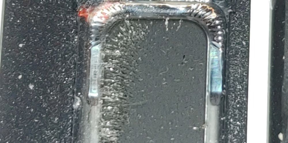 Closeup view of a small computer speaker membrane. Along one side of the speaker is a nearly solid line of steel shavings/dust from the large amount of weld grinding that occurs in our home)