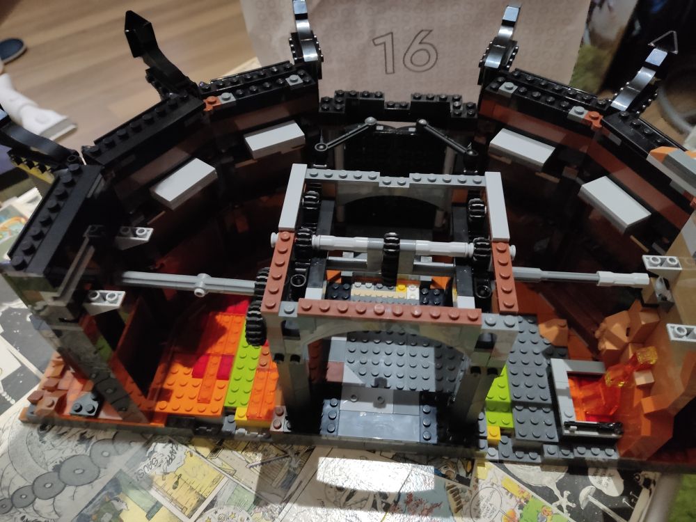 There's a square frame on the baseplate from bag 15 with a mechanism in the middle and two axles to the left and right. The square baseplate has been slid into the rest of the tower, the former U shape is now a half circle. 
Empty bag 16 is in the background.