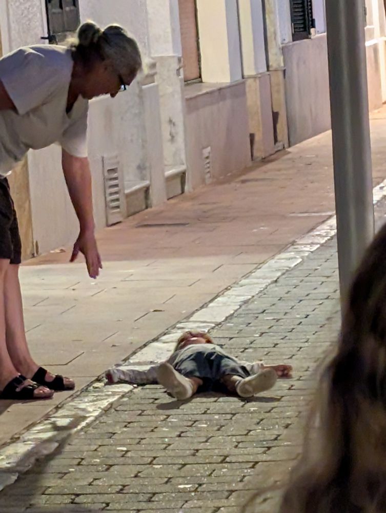 A child laying in a pedestrianized street.