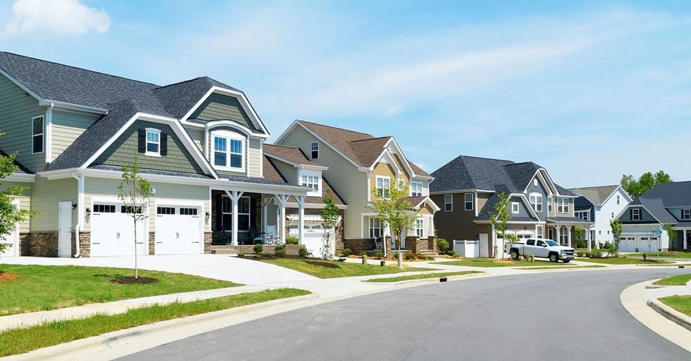 ground view of a suburb lined with big houses, young trees, and empty lots