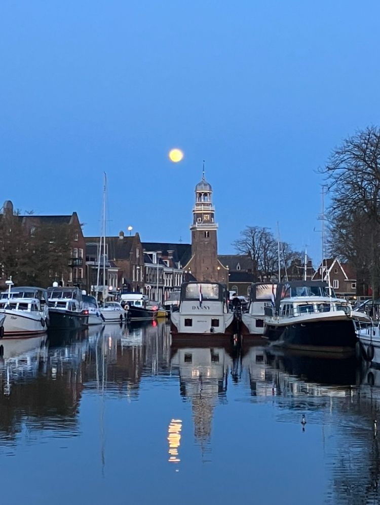 Weerspiegeling maan en boten in water