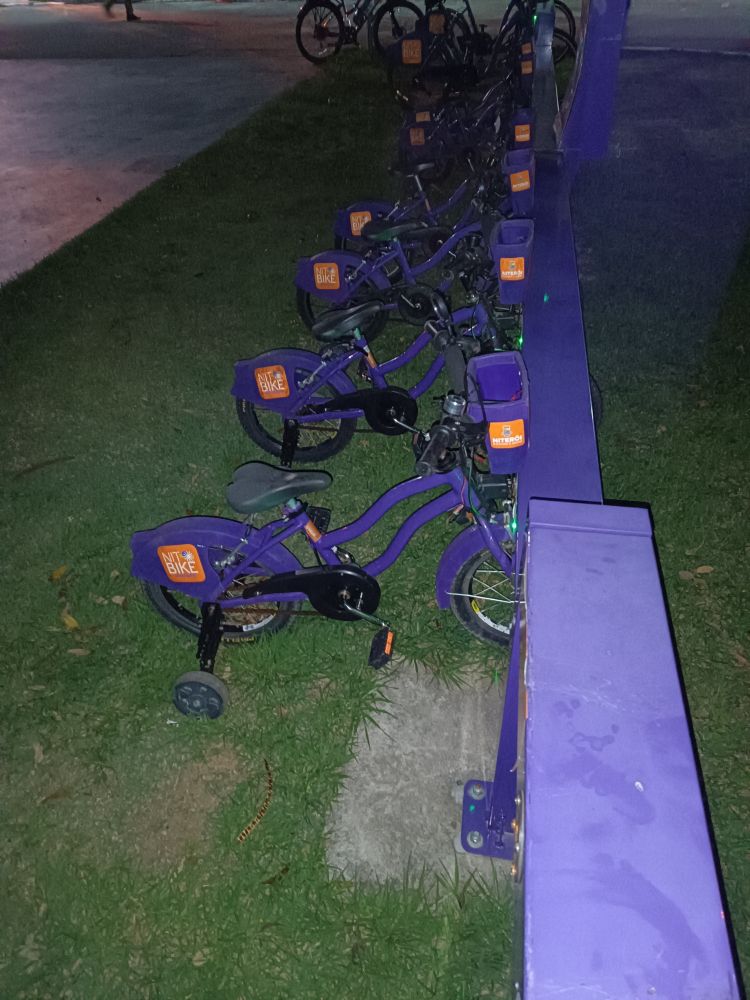 ponto de bicicletas da prefeitura de Niterói. na foto estão várias bicicletas enfileiradas. elas são roxas, têm tamanho infantil e rodinhas de apoio.