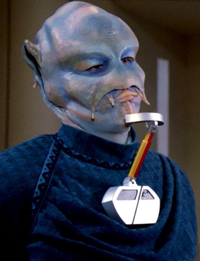 A blue alien known as a benzite from star trek the next generation pointing with his smoking apparatus 