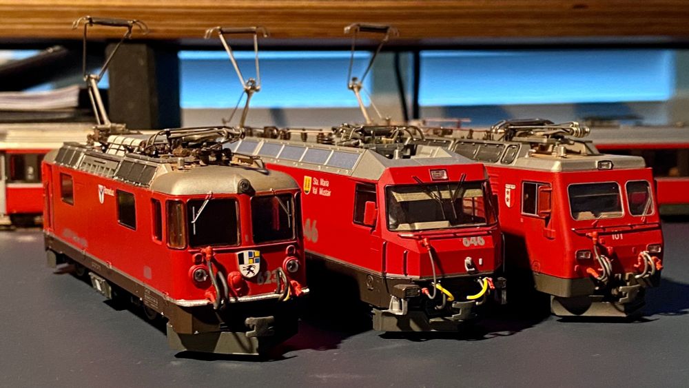 Three recognizable Swiss meter gauge locomotives from BEMO in HOm gauge. Two are from the Rhaetian Railway, the left being a GE 4/4 II and the middle a GE 4/4 III. On the right stands a Furka-Oberalp HGE 4/4 II. All have been detailed with cabin blinds out of cardstock for the windows, subtle weathering, and fitted with hoses from the package that have been painted to match the prototype more closely.