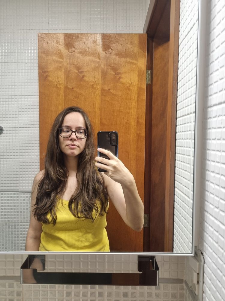 Foto no espelho. Tô com uma regata amarela e o cabelo (enorme - quase abaixo do peito) todo pra frente. Cabelo esse apelidado de "maria mijona" pois enorme e sem corte algum.