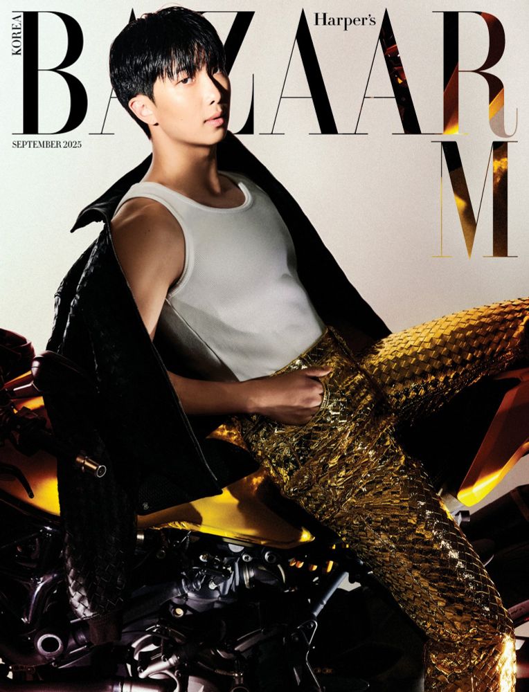 Namjoon is on the cover of Harper's Bazaar. He's perched on a motorcycle, reclining back with one hand in his pocket. He's wearing textured gold pants, a white tank top, and a black jacket falling off his shoulder.