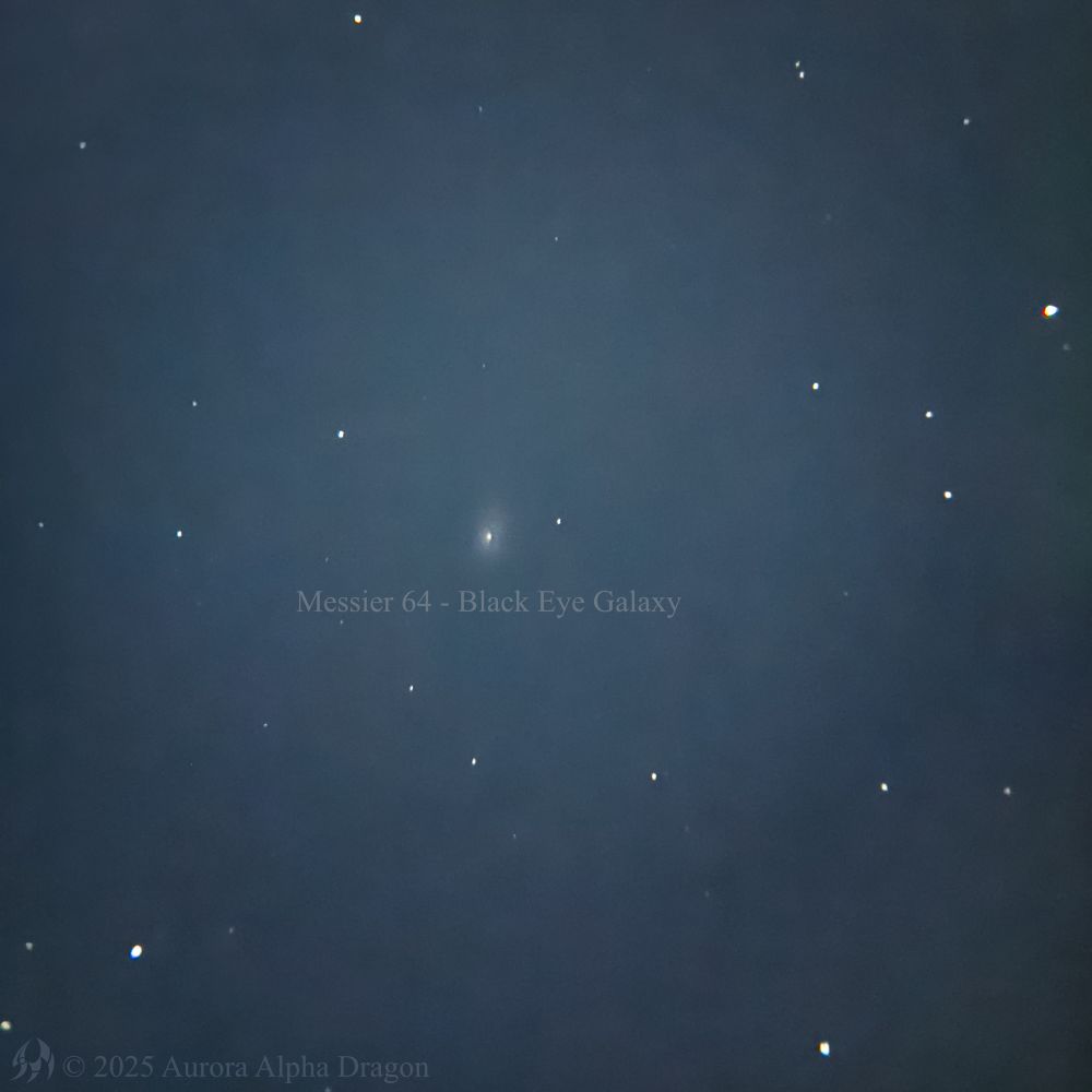 A photograph through a telescope showing a faint distant galaxy appearing as an orb of light with a faint dark disk called Messier 64, the Black Eye Galaxy.