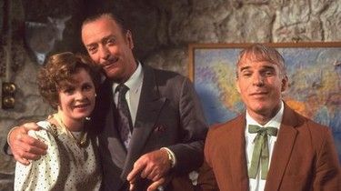 A woman, a man and another man standing in a room with a stone wall behind them and a picture of a world map