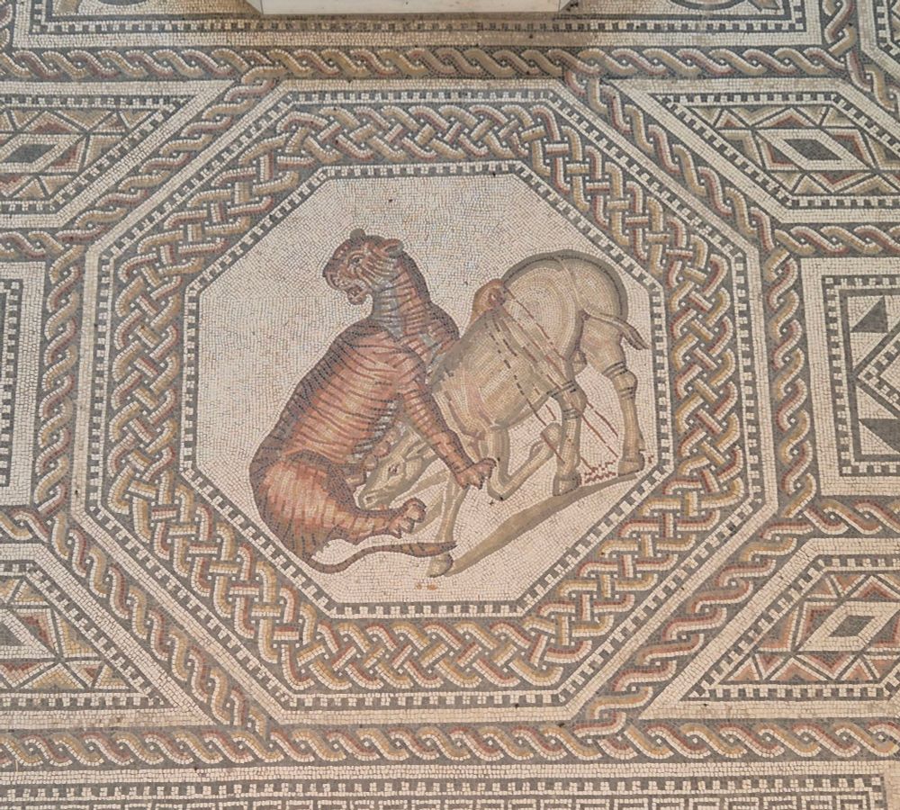 Detail of the mosaic: octogon with a tiger driving his claws into a horse, blood dripping from the horse's wounds. 