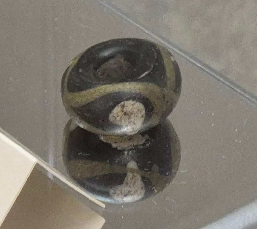 In the third medallion, there is only a white blob with some white color flowing down on one side, as the reflection in the mirror that the bead stands on shows. 