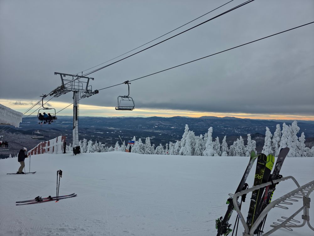View of the horizon from next to the top of 4 Runner. The trees are covered in snow, and there's a sliver of morning light between the distant mountains and the cloud cover