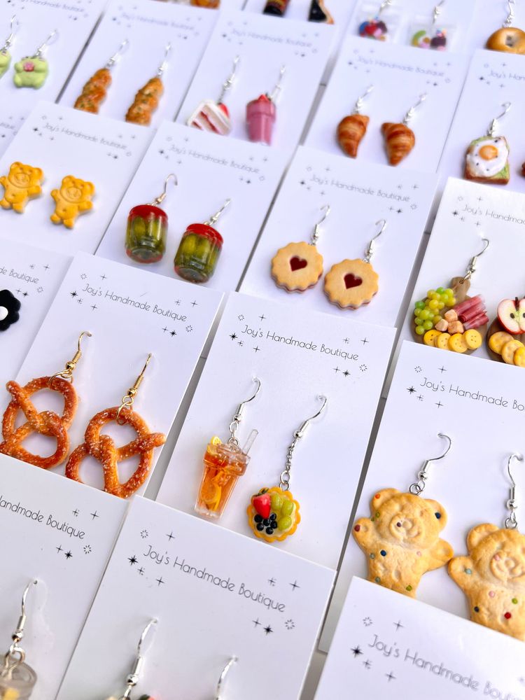 Multiple earrings sets by Joy, of miniature things we enjoy eating and enjoying, like pretzels, or jars of pickles or ravioli (with a bite taken out of one).