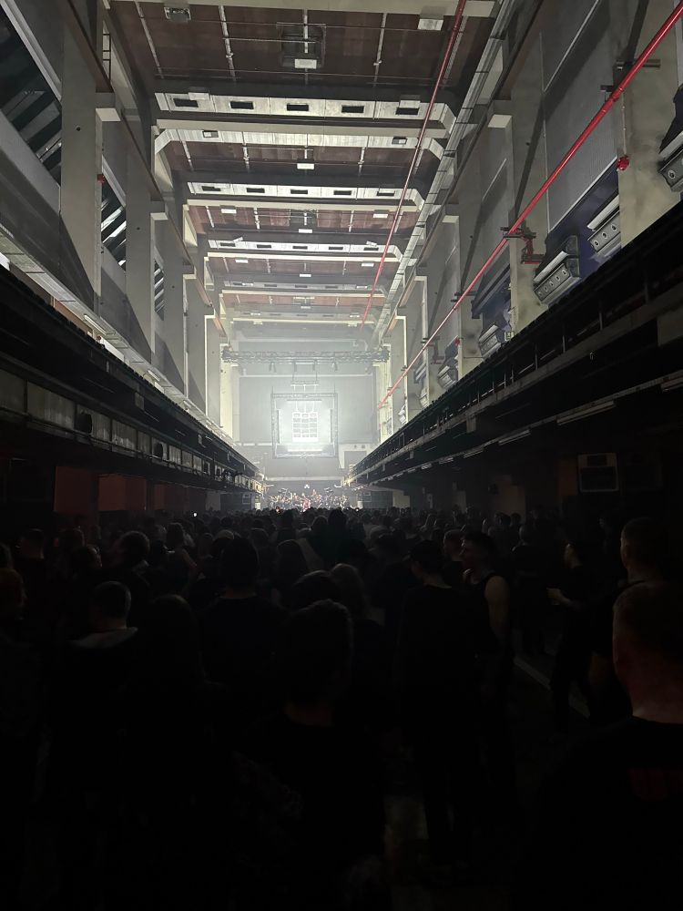 Das Bild zeigt eine große lange dunkle ehemalige Fabrikhalle in Erfurt, voll mit tanzenden Menschen, ganz vorne eine Dj im Licht