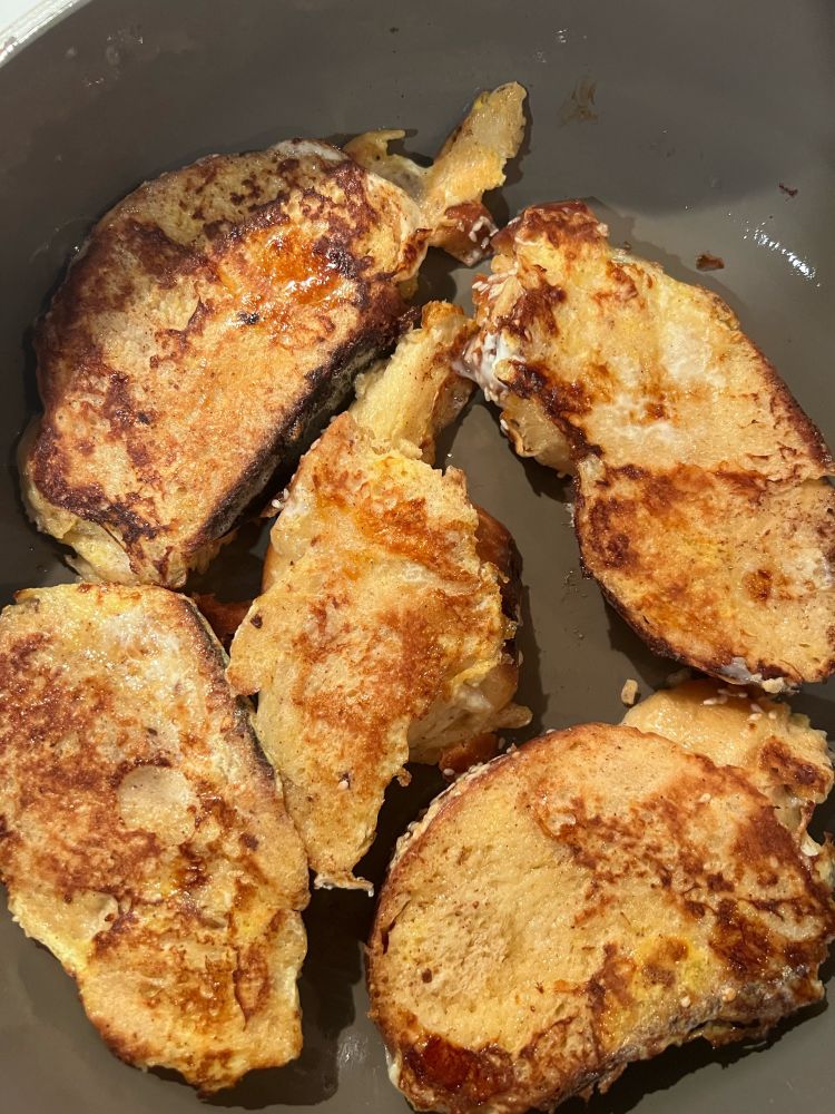 Five pieces of challah French toast in a pan