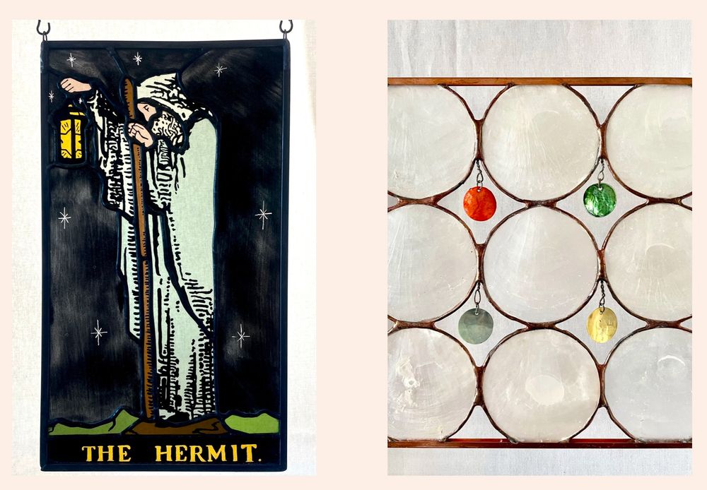a photo of two stained glass panels. One is a hand painted stained glass of the rider waite smith tarot card of the hermit, and one is not actually stained glass at all, but is capiz shell (aka windowpane oyster) and is 9 circles of shell stacked into a square 3 over 3, with little colored round shells dangling in the hollow spaces between the larger shells