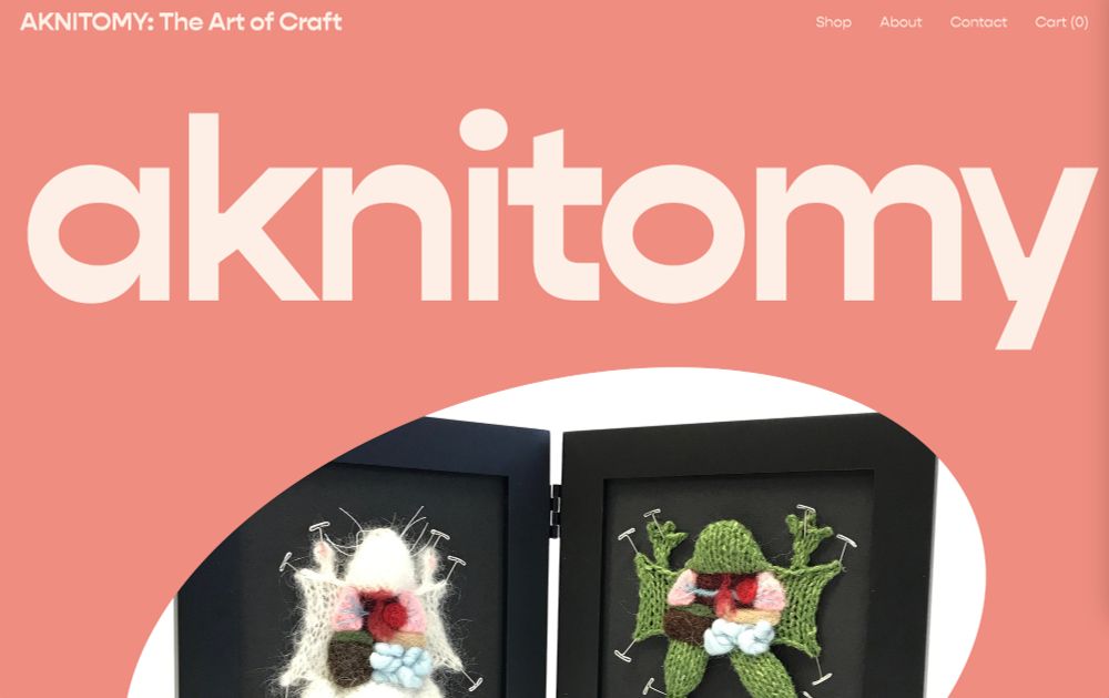 a screenshot of my website landing page. it’s titled Aknitomy: the art of craft, and it features an image of a knitted lab rat and knitted dissected frog pinned into a hinged black frame 