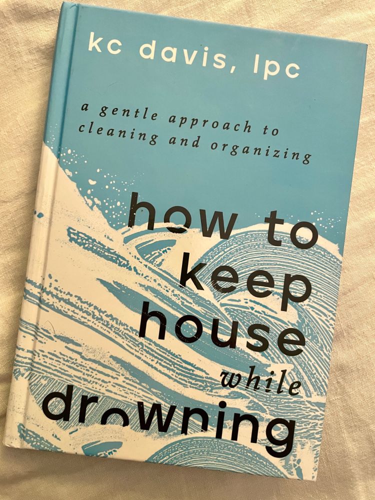 the blue and white cover of KC Davis’s How to Keep House While Drowning: A gentle approach to cleaning and organizing