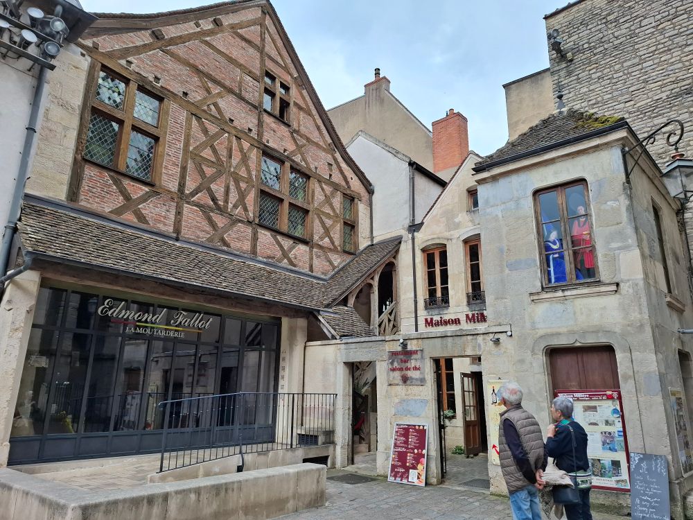 Maison à colombages et briques sur la gauche et petites maisons en pierres sur la droite. La maison à colombages abrite une boutique de moutarde car oui on est à Dijon !