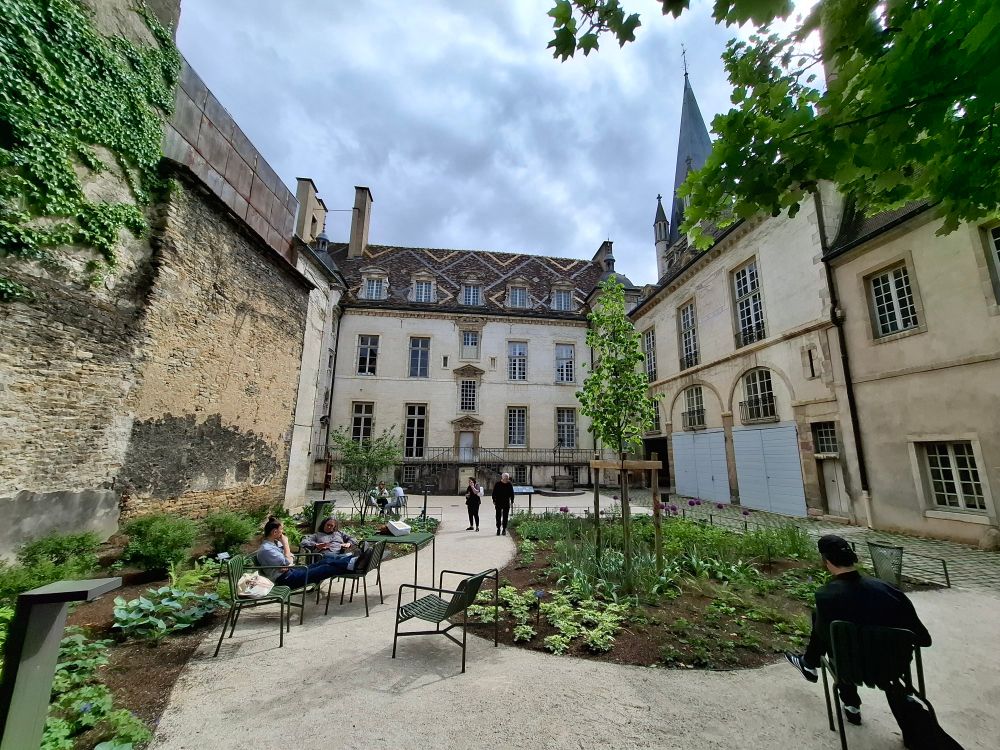 Petit jardin caché au centre de Dijon. Au fond un bâtiment avec un toit bourguignon soit avec des motifs géométriques. 