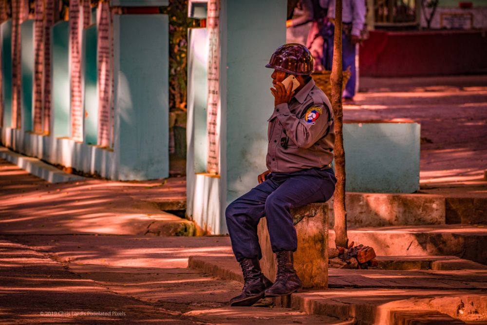 A Myanmar policeman relaxing and calling home