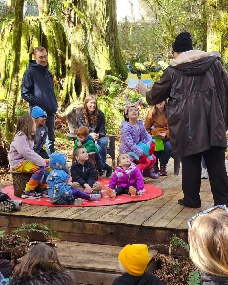 A Rooster Haus board member reading a story to families, amongst the trees