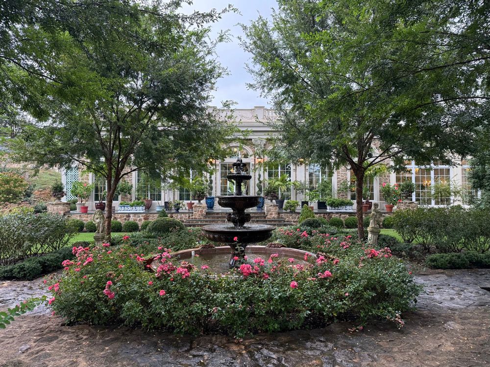 The back courtyard overlooking the outside of the orangery. A large fountain adorned with pink roses leads to the main entrance and of the greenhouse.