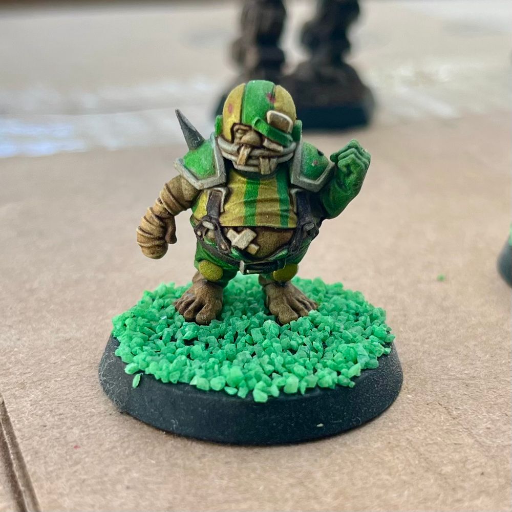 A Halfling miniature wearing yellow and green jersey with an American football helmet on his head. 