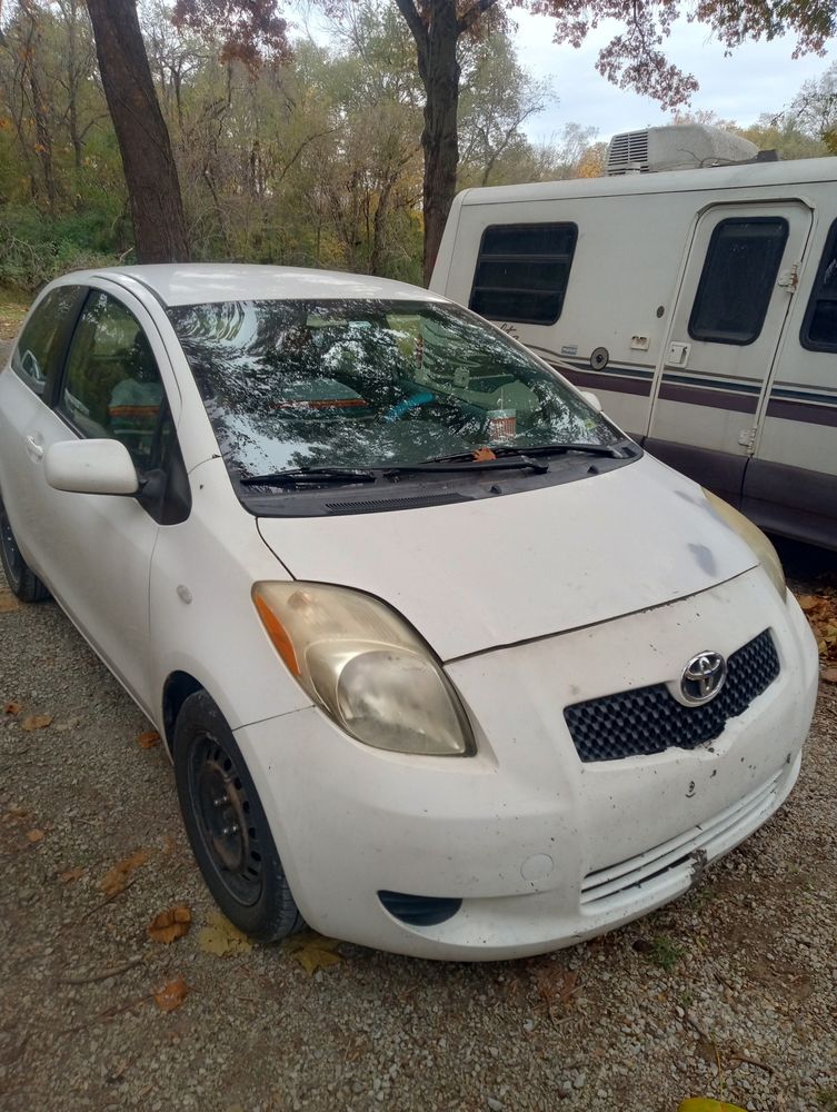 A beat up white 2007 Yaris.