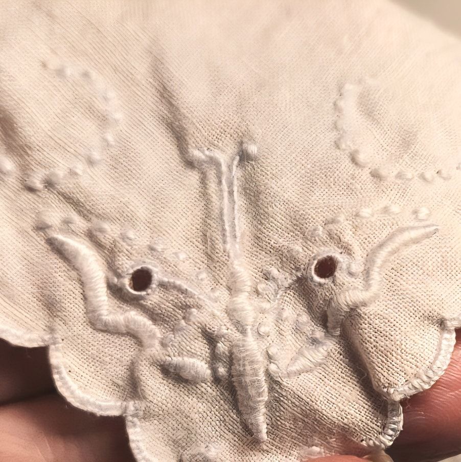 Detail view of vintage white handkerchief embroidered with an all white butterfly or moth, to be used in this character's costume.