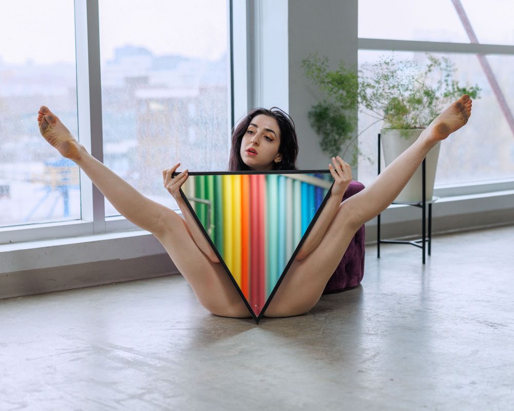 woman holding triangular mirror that reflects colorful paper rolls