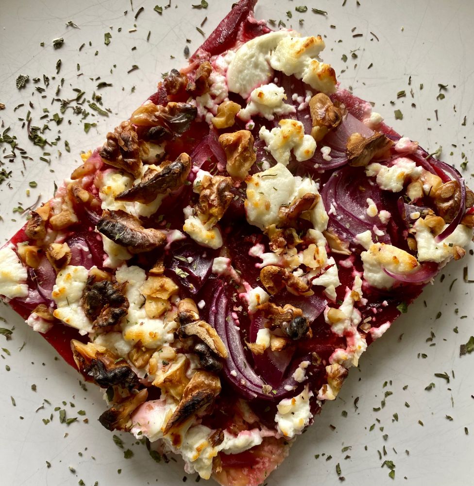 Ein fast quadratisches Stück ist auf einem weißen Teller angerichtet und mit etwas Kräutern als Deko aufgehübscht.