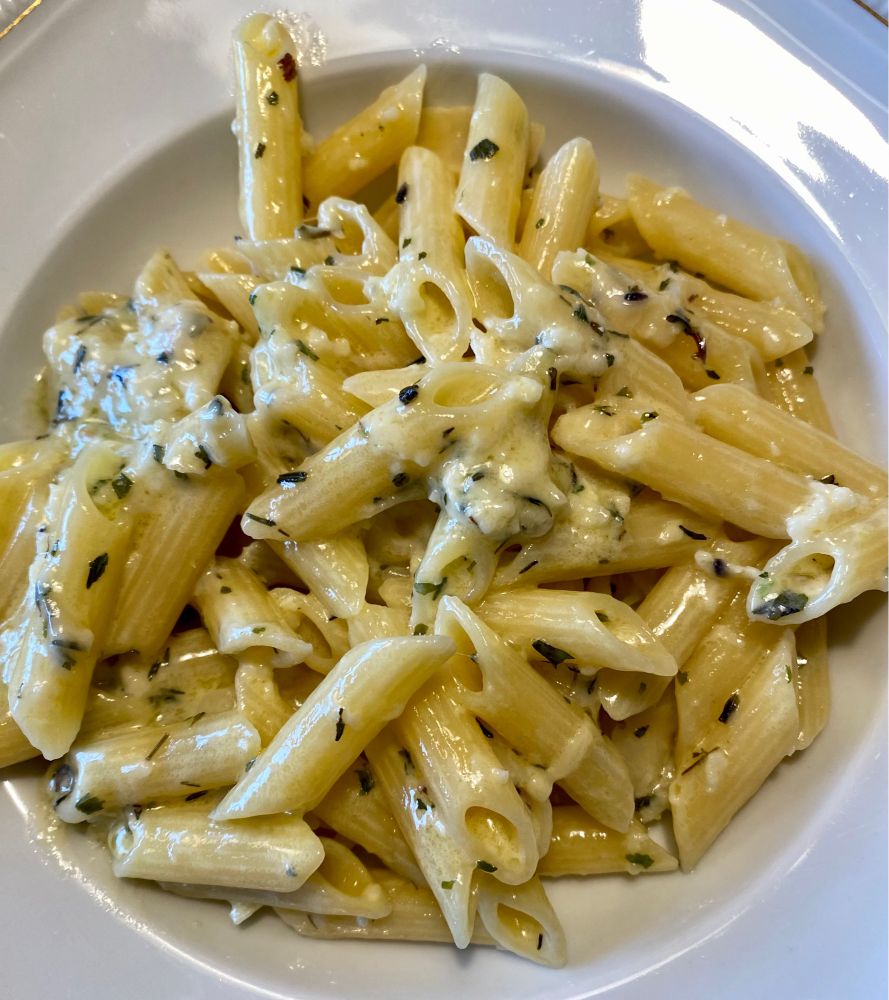 Das Nudelgericht ist ohne Gedöhns auf einem weißen, tiefen Teller angerichtet