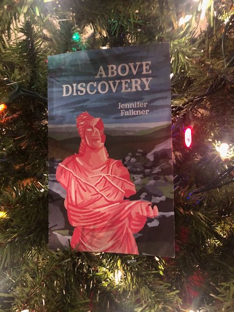 The book Above Discovery by Jennifer Falkner (Invisible Publishing) sits nestled in the branches of a Christmas tree