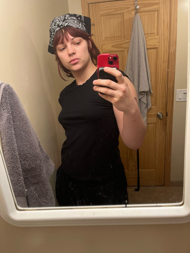 a gorgeous beautiful dyke-ish ingénue with a mustache and a black bandana posed gracefully in the mirror with incredible side boob