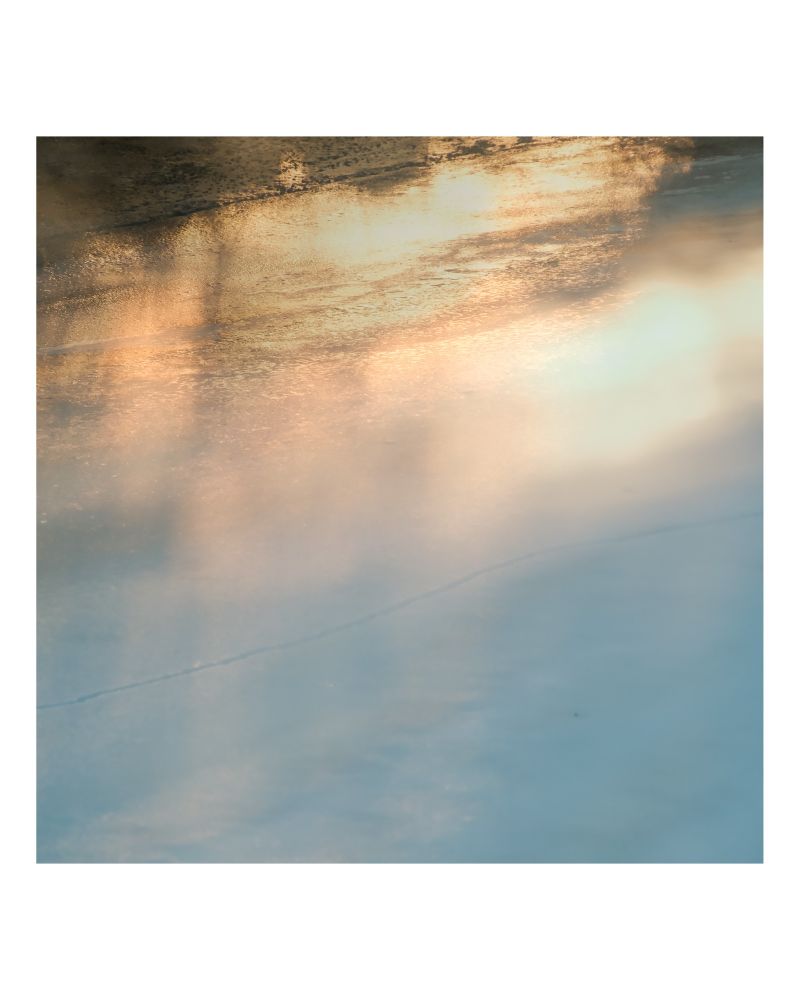 Abstract photo of sunrise light reflecting on icy creek.