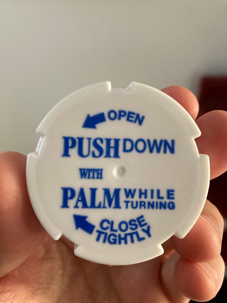 pill bottle top that says PUSH DOWN WITH PALM WHILE TURNING except those words are all weighted differently and distributed in an unreadable mess around the top