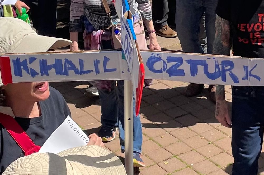 sign reading "hands off" on one axis and "Khalil & Öztürk" on the other
