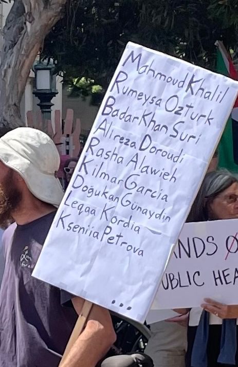 sign that is just a list of names: Mahmoud Khalil, Rümeysa Öztürk, Badar Khan Suri, Alirezi Doroudi, Rasha Alawieh, Kilmar Garcia, Doğukan Günaydın, Leqaa Kordia, Kseniia Petrova" followed by ellipsis