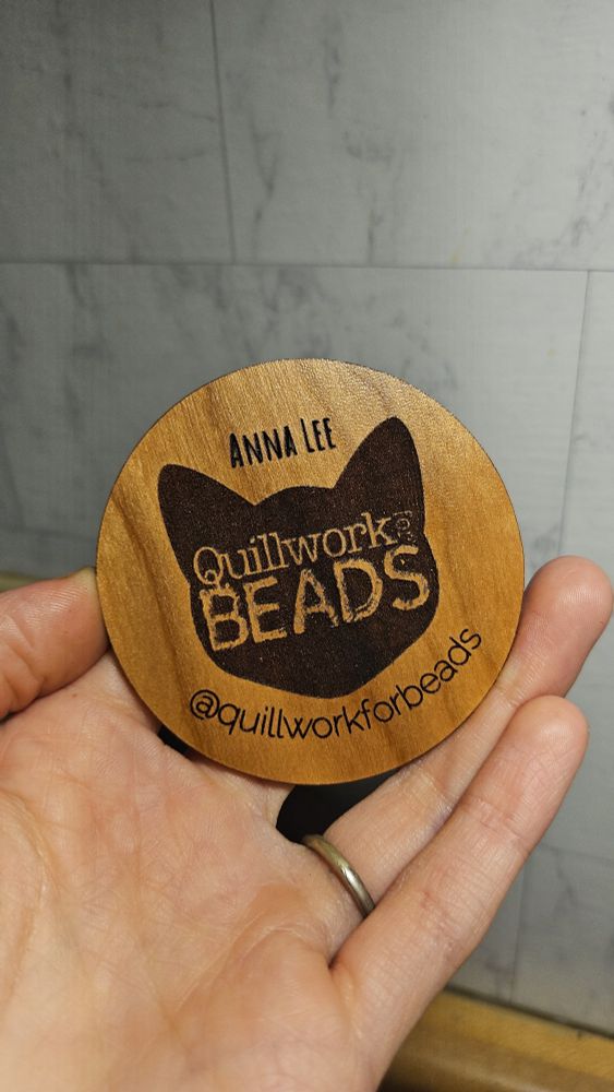 A laser-cut circle with the artist's name and logo engraved on the surface. Medium hardwood, proofgrade material.