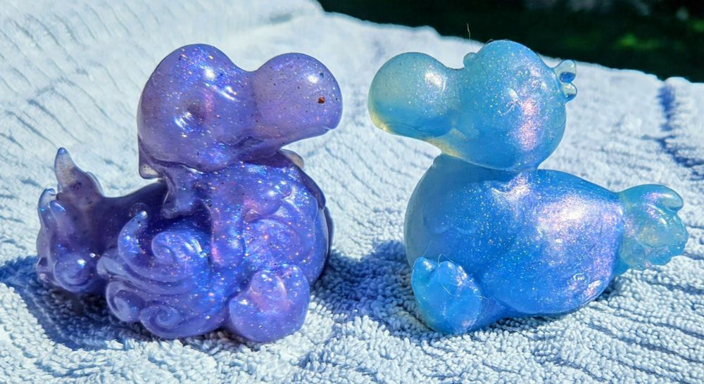 2 Dodo shaped squish, one purple one blue, put on a table facing each other 